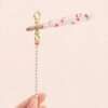 Assorted wholesale beaded joint holder sticks featuring gold rings, colorful crystal beads, and pearls on a ceramic plate