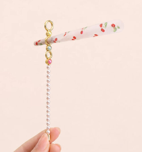 Assorted wholesale beaded joint holder sticks featuring gold rings, colorful crystal beads, and pearls on a ceramic plate