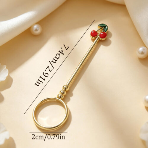 Gold joint holder ring topped with cute red enamel cherries held on a finger